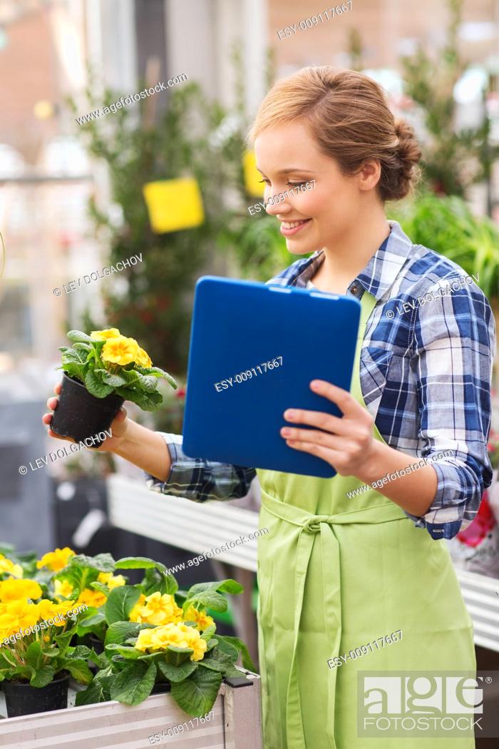 Stock Photo: people, gardening, technology and profession concept - happy woman or gardener with tablet pc computer and flowers in greenhouse.