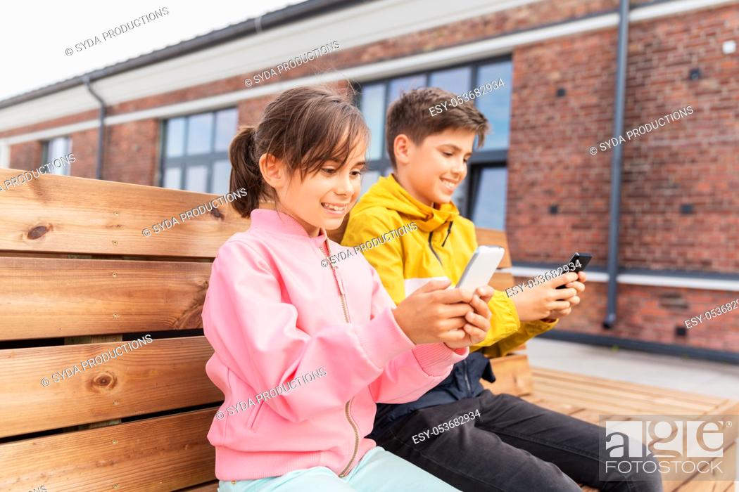 Stock Photo: children with smartphones sitting on street bench.