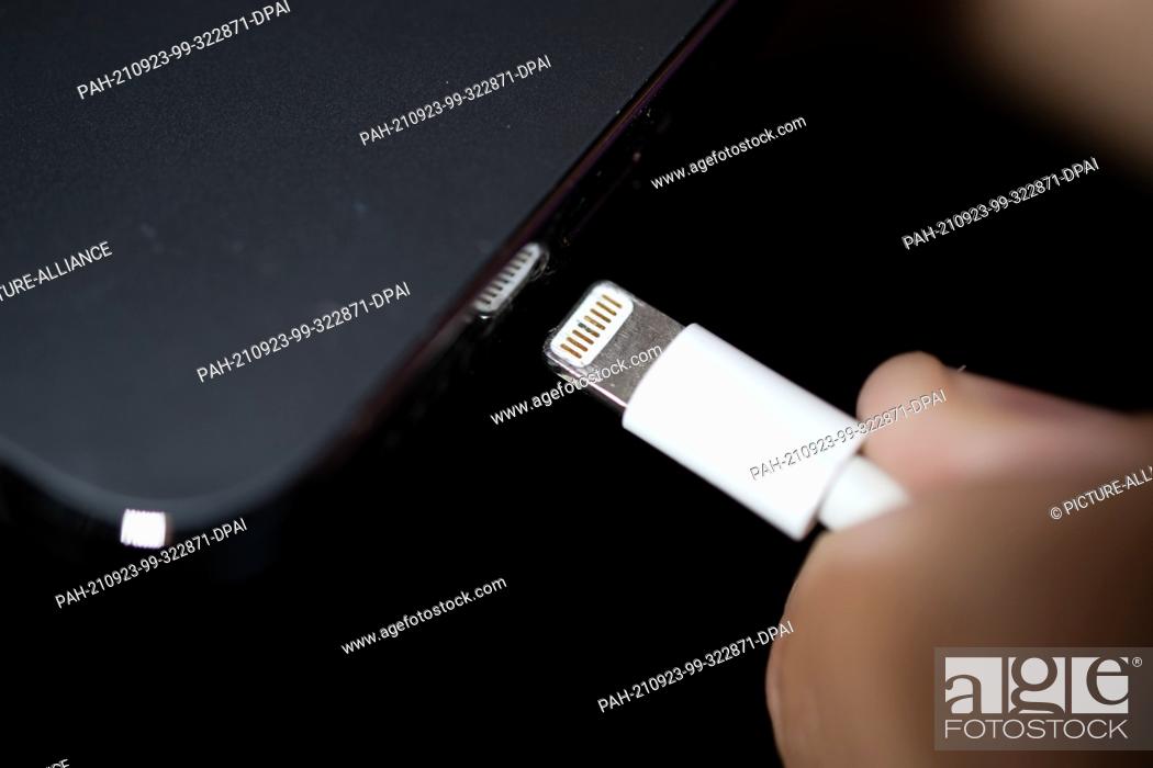 Stock Photo: 22 September 2021, Lower Saxony, Oldenburg: A Lightning charging plug is inserted into an Apple iPhone. The EU Commission presents a proposal for a uniform.