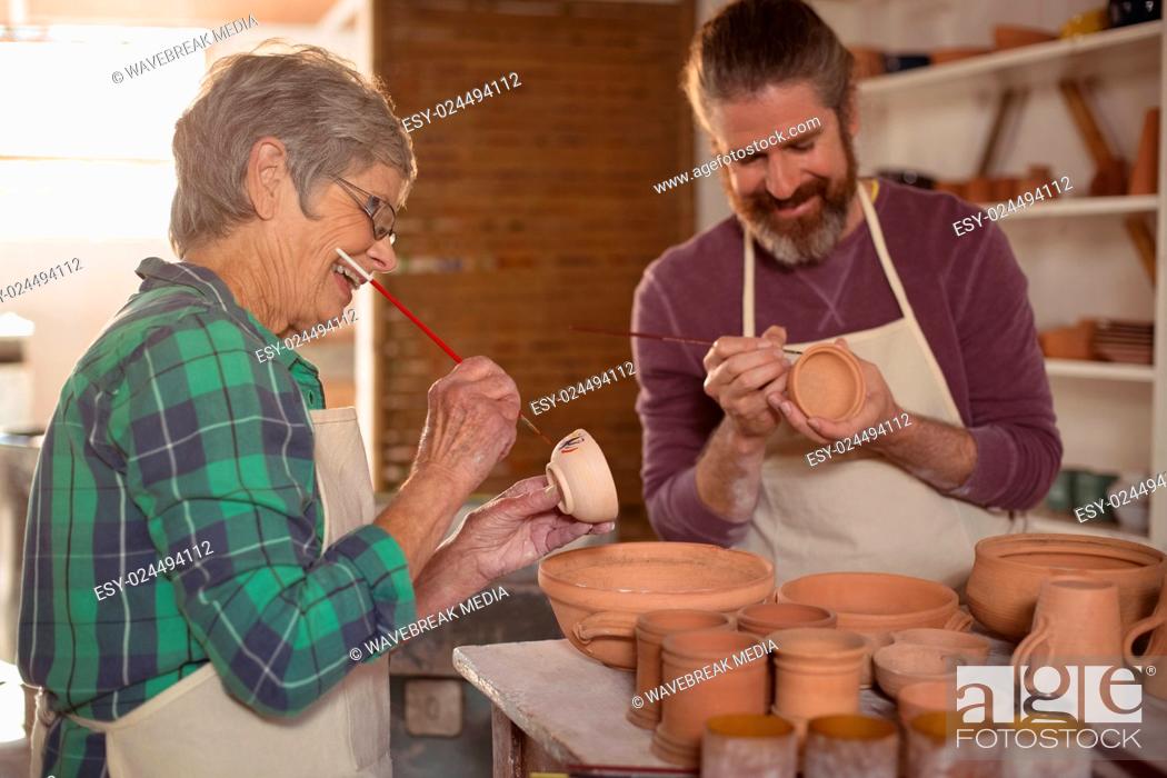 Stock Photo: Male and female potter painting pots.