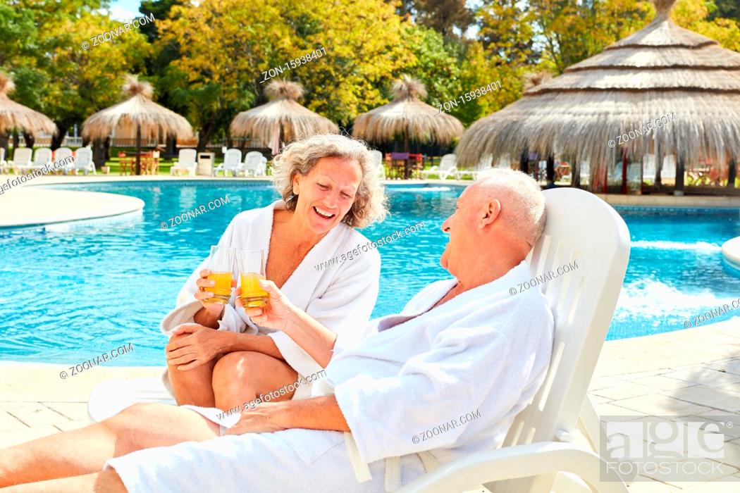 Stock Photo: Glückliches Paar Senioren sitzt mit Orangensaft am Pool vom Hotel.