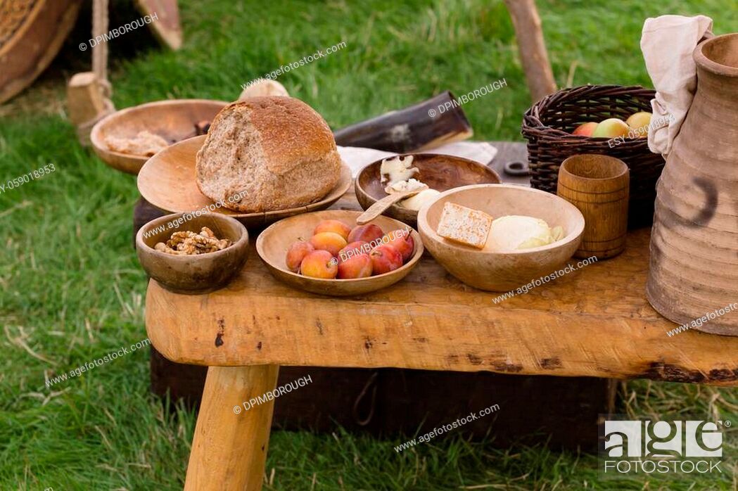 Stock Photo: Typical selection of Medieval food including bread, butter, cheese, fruit and nuts served in wooden bowls or trenchers.