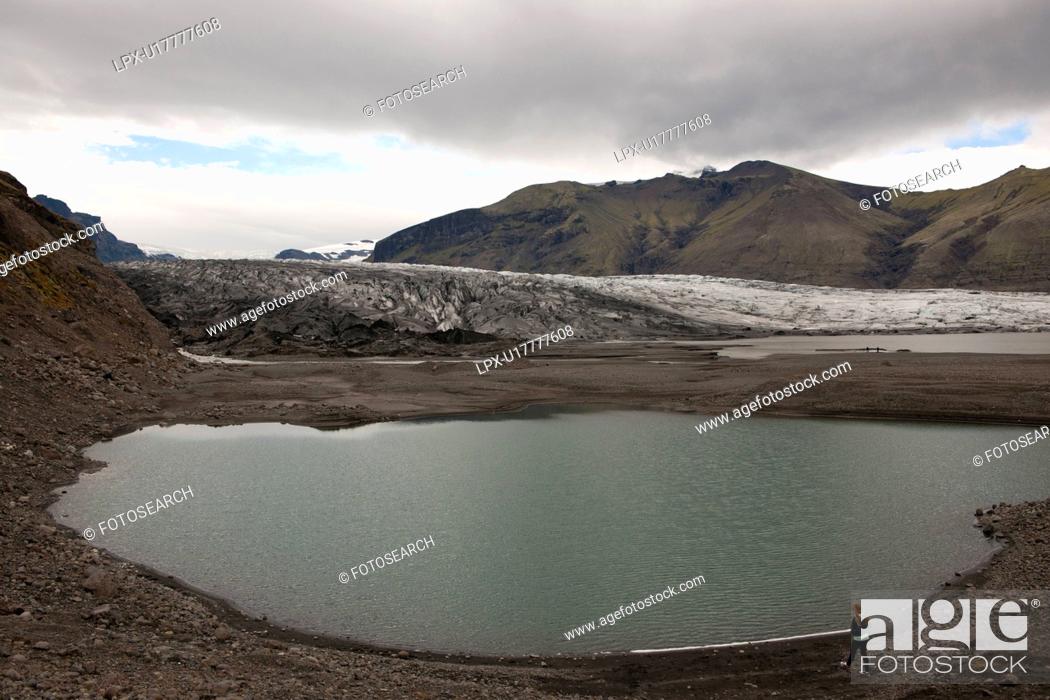 Stock Photo: Glacier and glacial lake surrounded by mountains on cloudy day.