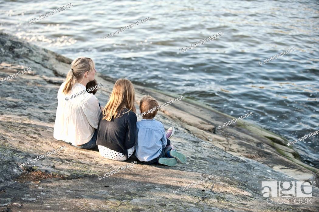 Stock Photo: Mother with three children sitting at water, Nacka, Sweden.