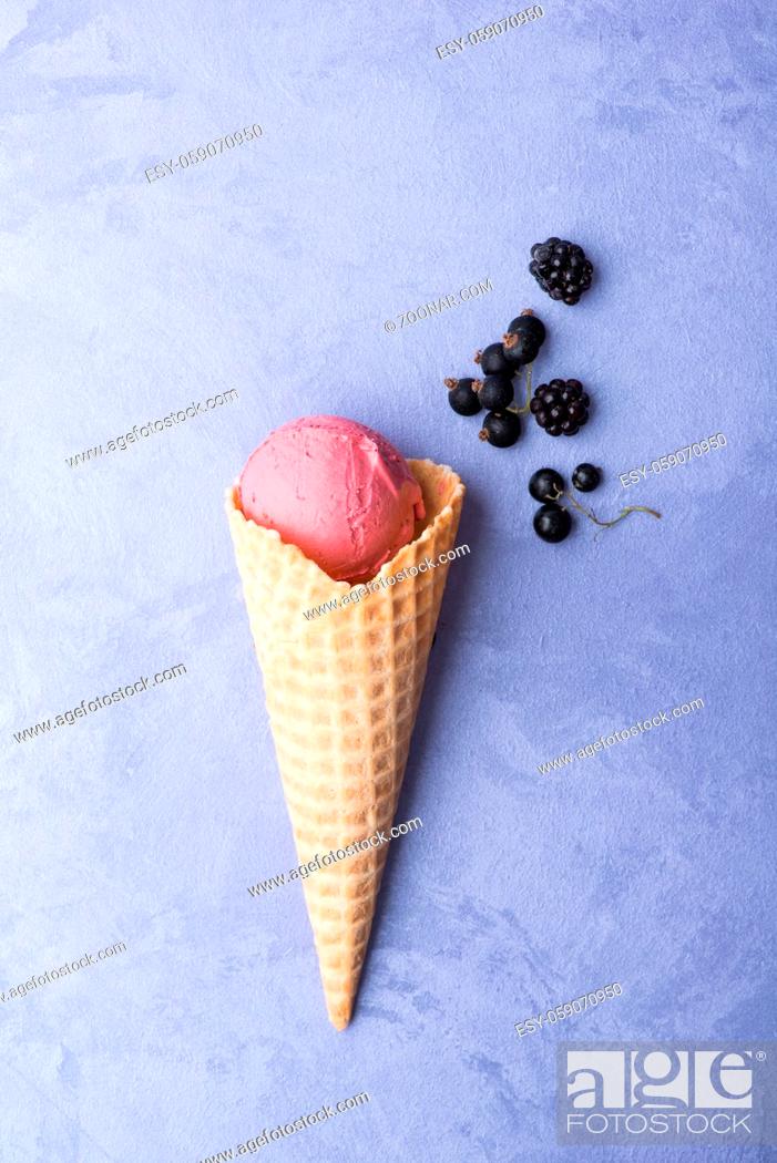 Stock Photo: ice cream with berries in a waffle horn on an ornamental purple background, top view.