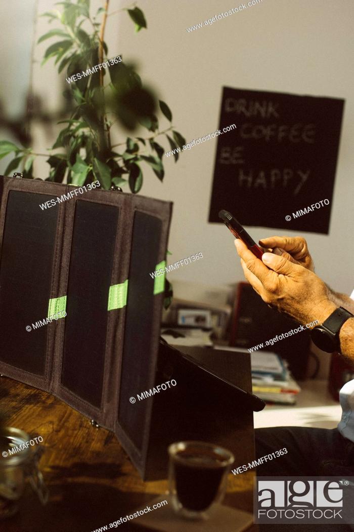 Stock Photo: Businessman with smart phone charging tablet PC with photovoltaic solar panel.