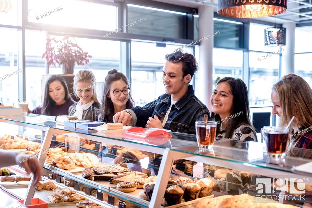 Stock Photo: Young male student and female friends queueing at cafe counter.