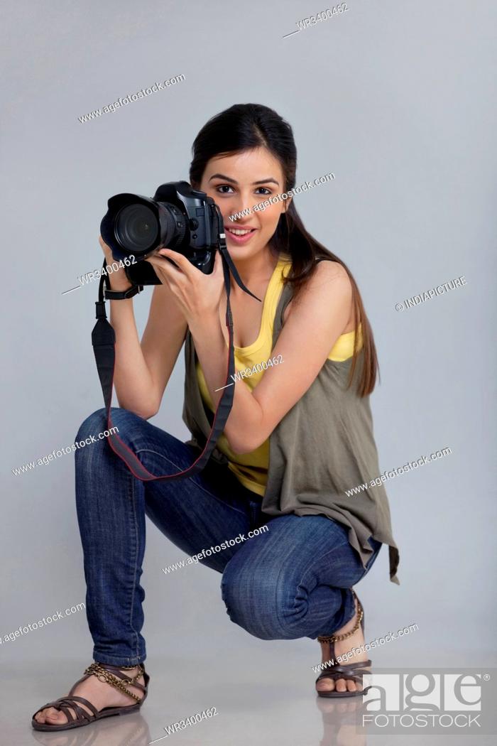 Stock Photo: Full length of smiling female photographer with camera in her studio.