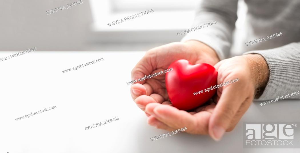 Imagen: cupped senior man hands with red heart shape.