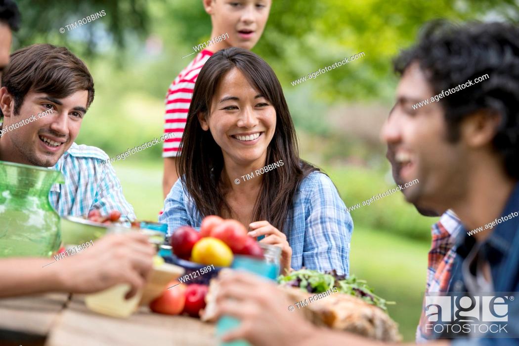 Stock Photo: A summer party outdoors. Adults and children around a table.