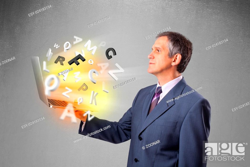 Stock Photo: Middle aged businessman holding laptop with colorful letters.