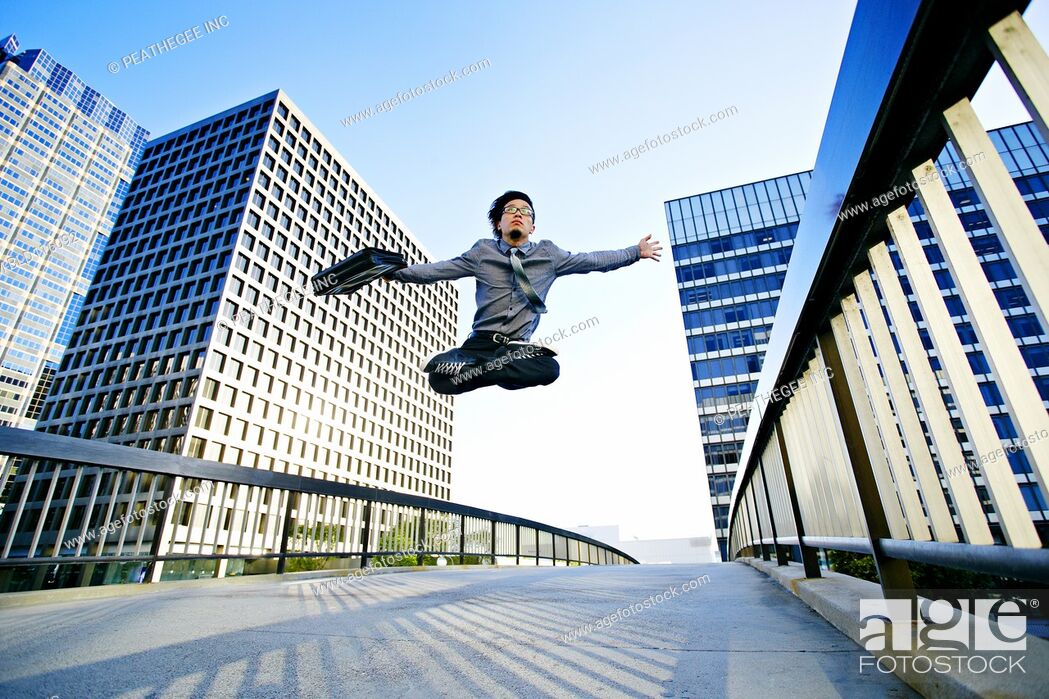 Stock Photo: Asian businessman leaping on urban walkway.