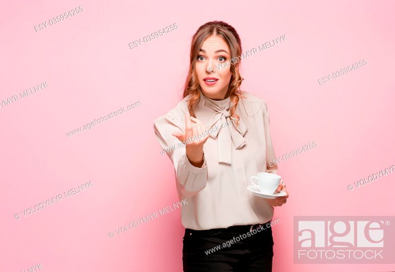 Imagen: The serious frustrated young beautiful business woman with empty cup on pink studio background.