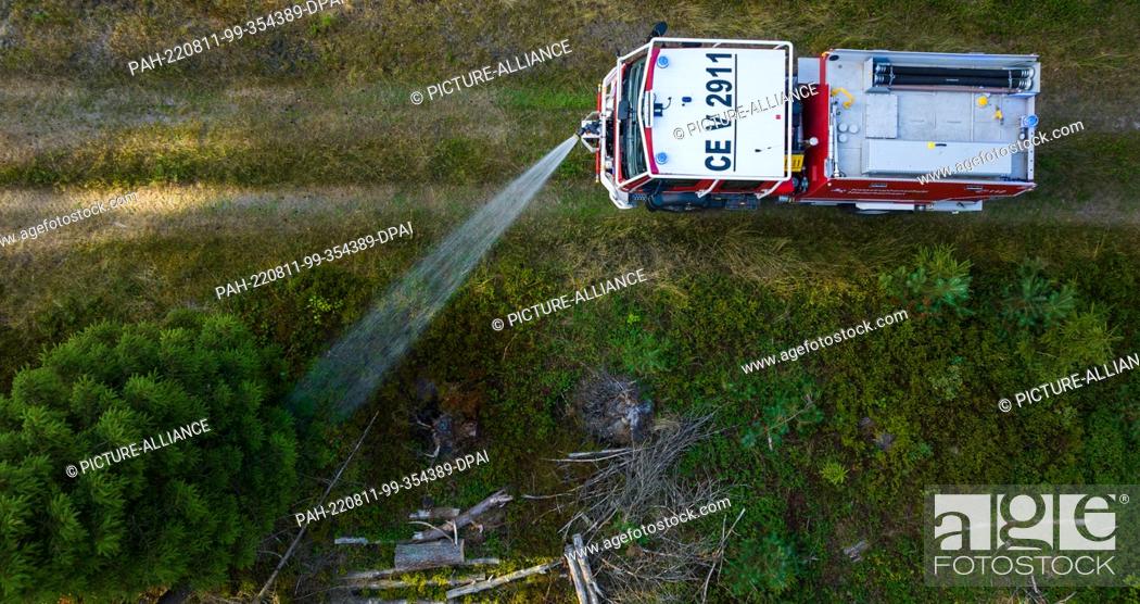Stock Photo: PRODUCTION - 09 August 2022, Lower Saxony, Wietzendorf: Volunteer firefighters practice the use of the forest fire fighting tanker ""CCFM 3000""(recording with.