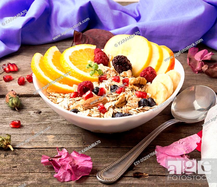 Stock Photo: Healthy breakfast. Muesli with orange fruit, apple, pomegranate, nuts, banana and honey in white bowl over on old wooden table.