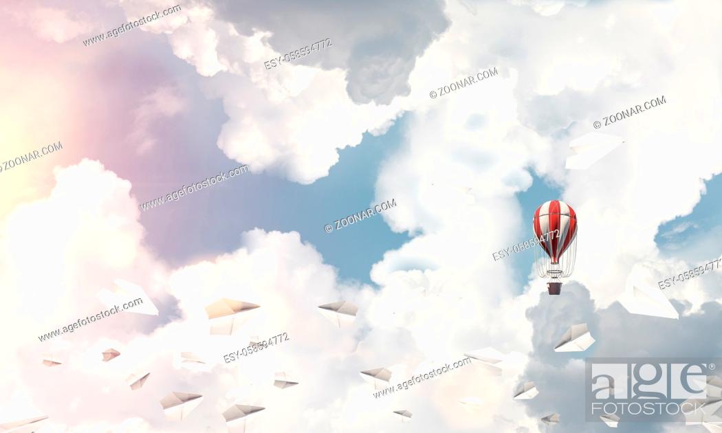 Photo de stock: Colorful aerostat flying among paper planes and over the blue cloudy sky. 3D rendering.