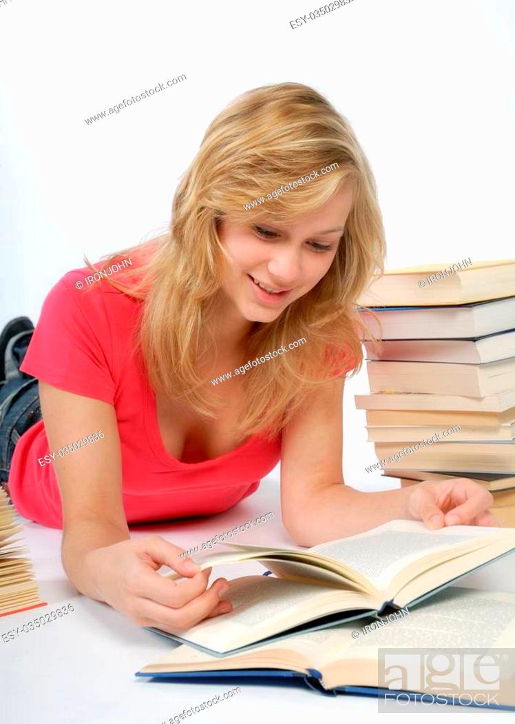 Stock Photo: Blonde girl reading a book with a stack of bokks beside her.