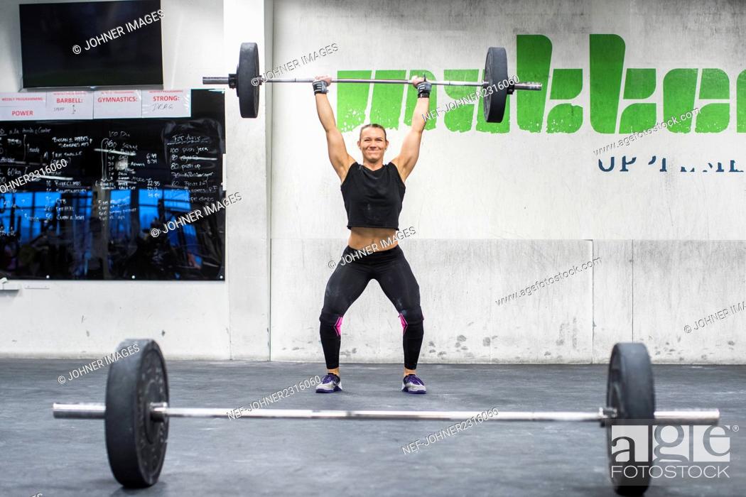 Stock Photo: Woman lifting barbell in gym.
