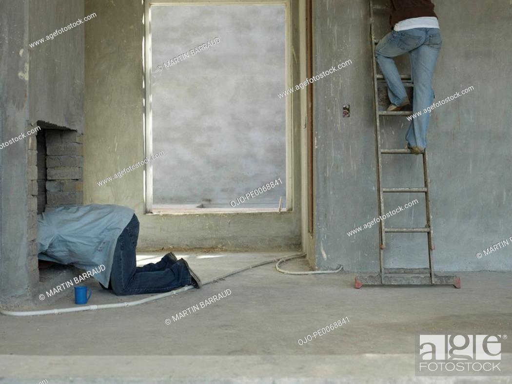 Stock Photo: Man in chimney and woman on ladder in house under construction.