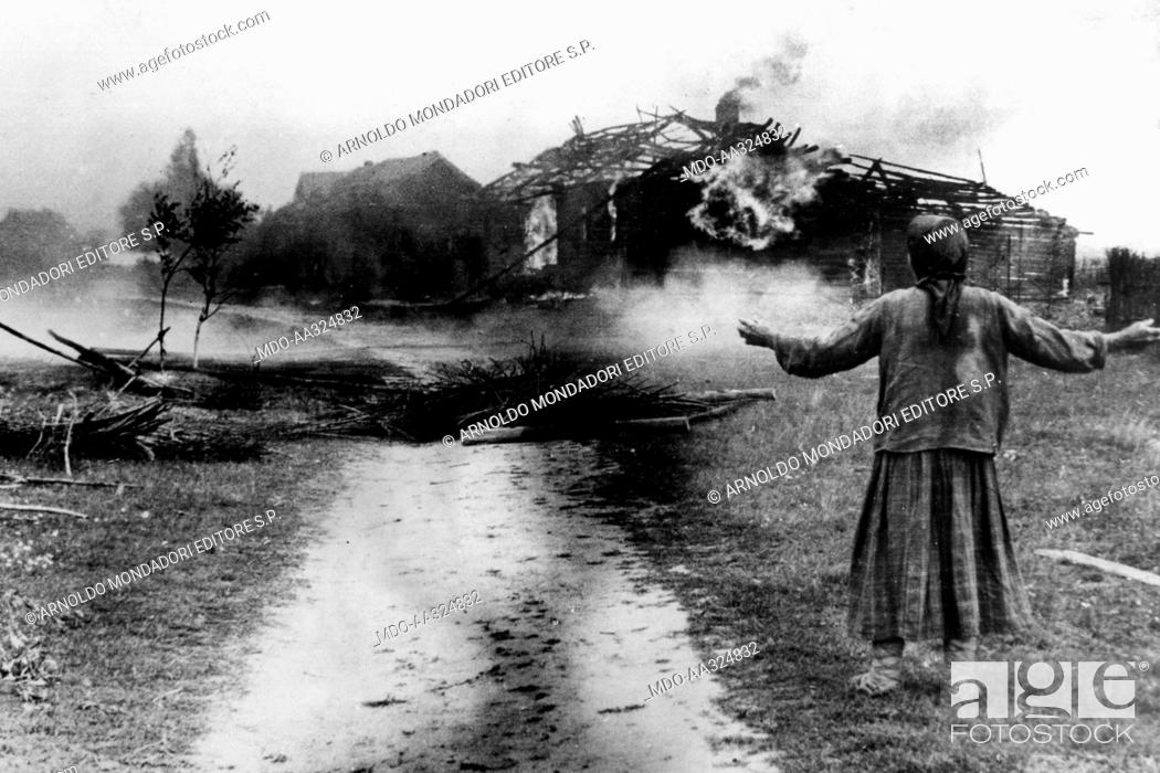Stock Photo: A Russian peasant woman's house burns. A Russian peasant woman watches her burning house on the southern front. August 1941.
