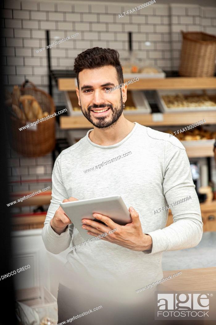 Photo de stock: Bakery owner holding digital tablet while looking at the camera.