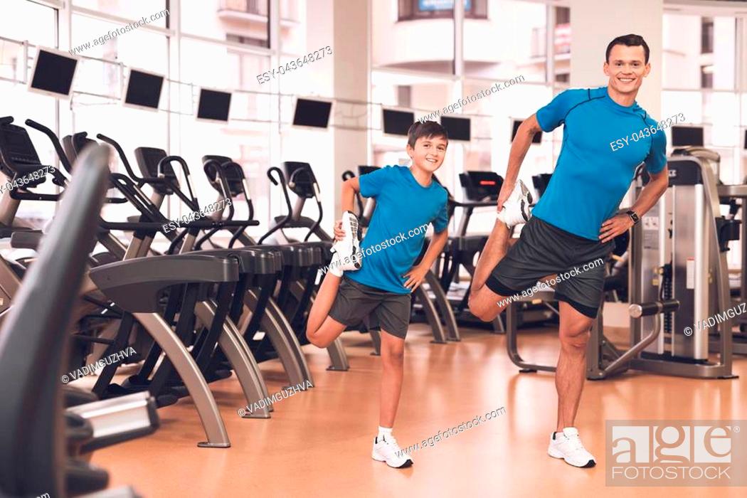 Stock Photo: Father with his son in the same clothes in the gym. Father and son spend time together and lead a healthy lifestyle. A man with a boy does a warm-up before.