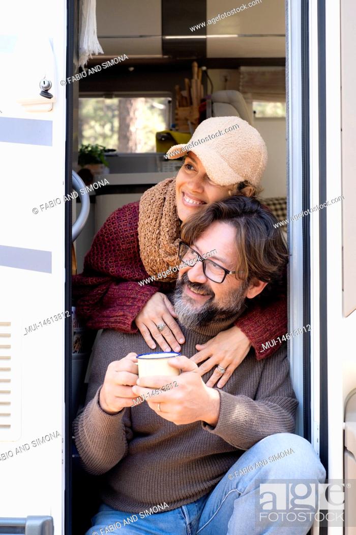 Stock Photo: Van life and alternative off grid life and vacation leisure time for happy couple man and woman sitting on the door of their camper van.