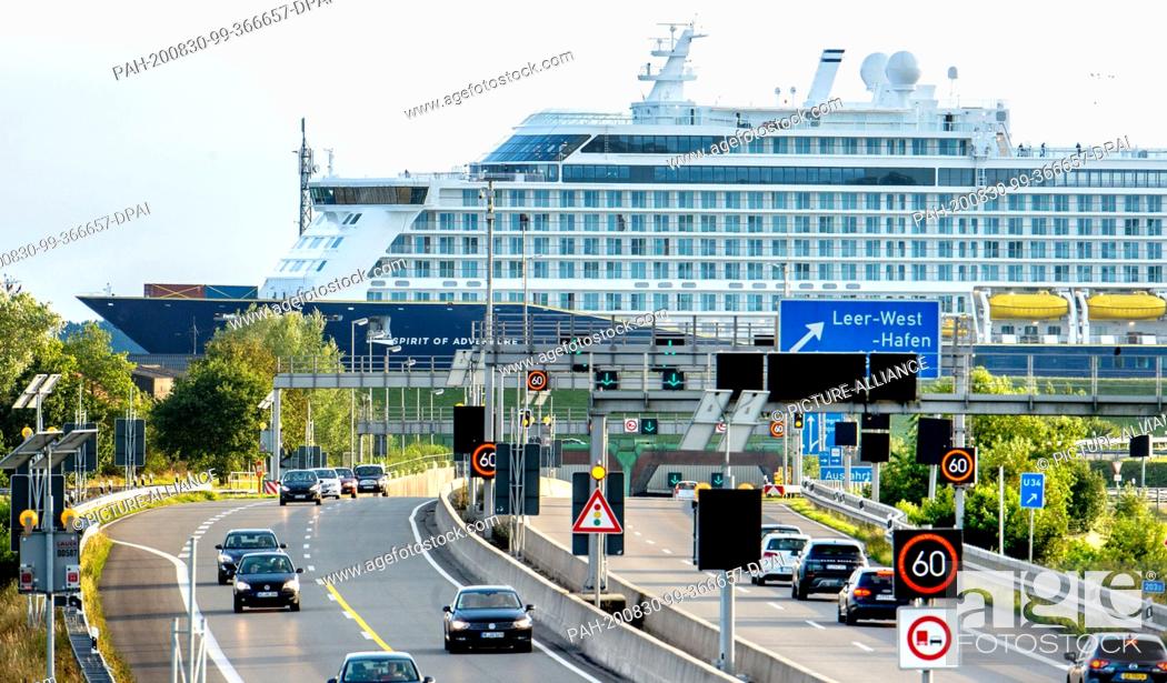 Stock Photo: 30 August 2020, Lower Saxony, Leer: Cars are on the A31 motorway, while the new cruise ship ""Spirit of Adventure"" is passing through the Ems Tunnel.