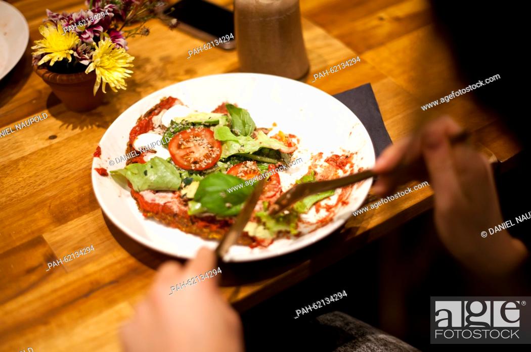 Stock Photo: A guest eats a vegan pizza in the newly opened restaurant 'Rawtastic' in Berlin, 23 September 2015. The restaurant offers different raw dishes.
