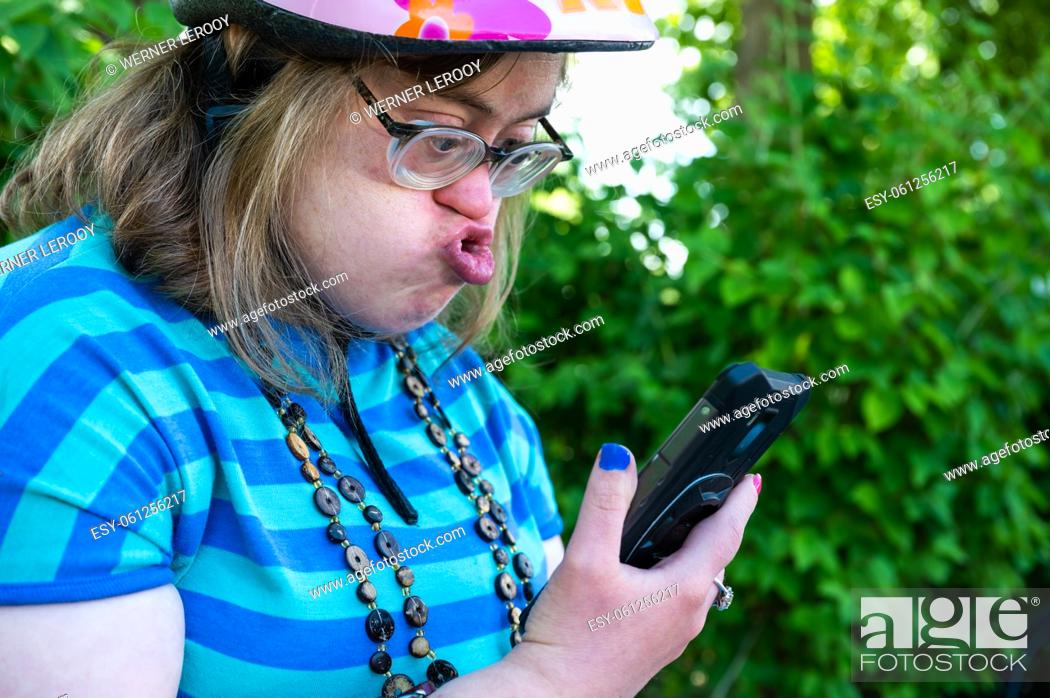 Photo de stock: Portrait of a 39 year old white woman with the Down Syndrome, having a video call with her family outdoors, Tienen, Belgium.