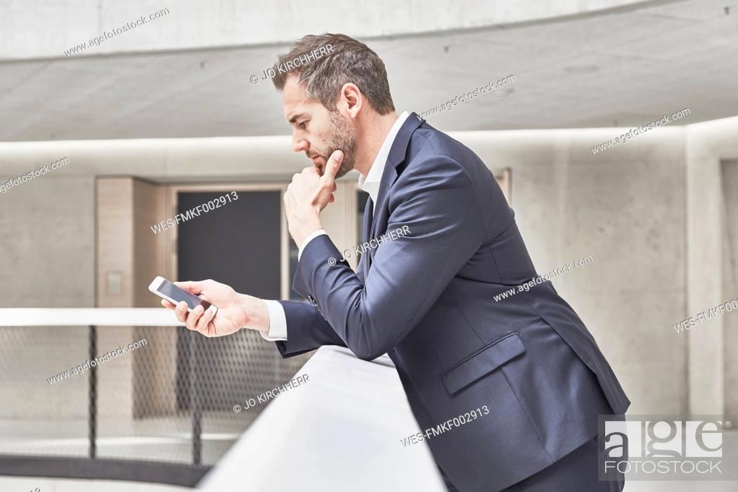 Stock Photo: Businessman in office building looking at cell phone.