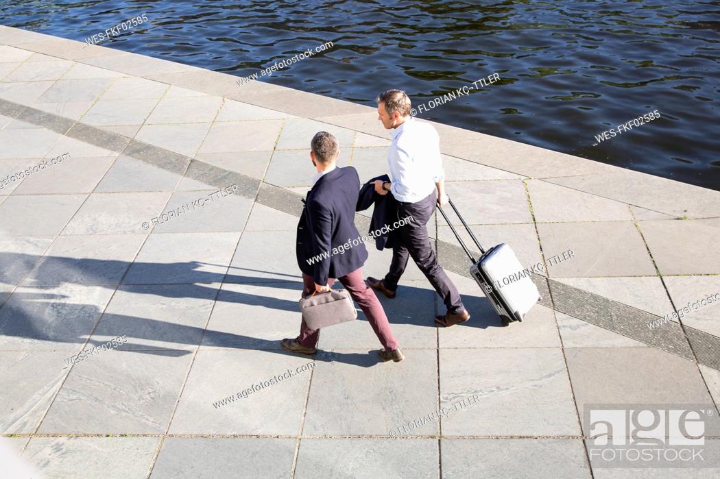 Stock Photo: Two businessmen walking and talking at the riverbank.