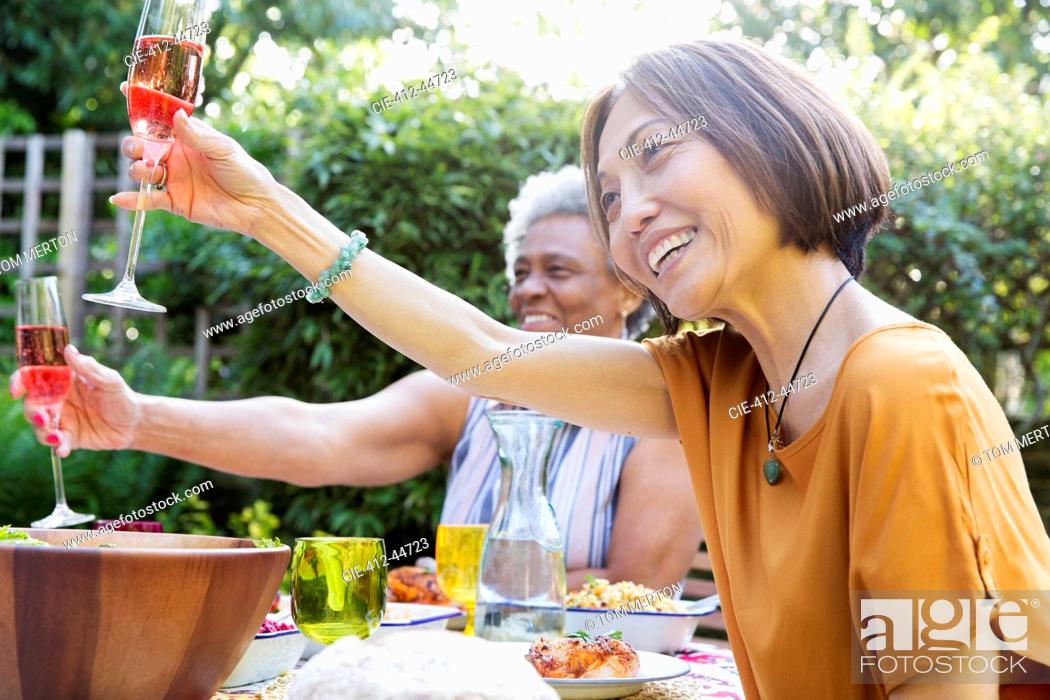 Stock Photo: Happy active senior women toasting rose wine at garden party.