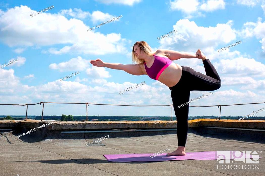 Stock Photo: Young woman doing yoga on the roof of a building.