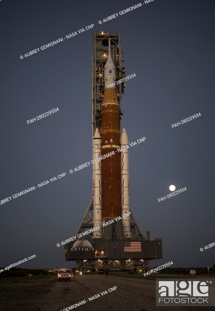Stock Photo: The Moon is seen rising behind NASA’s Space Launch System (SLS) rocket with the Orion spacecraft aboard atop a mobile launcher as it rolls out to Launch Complex.