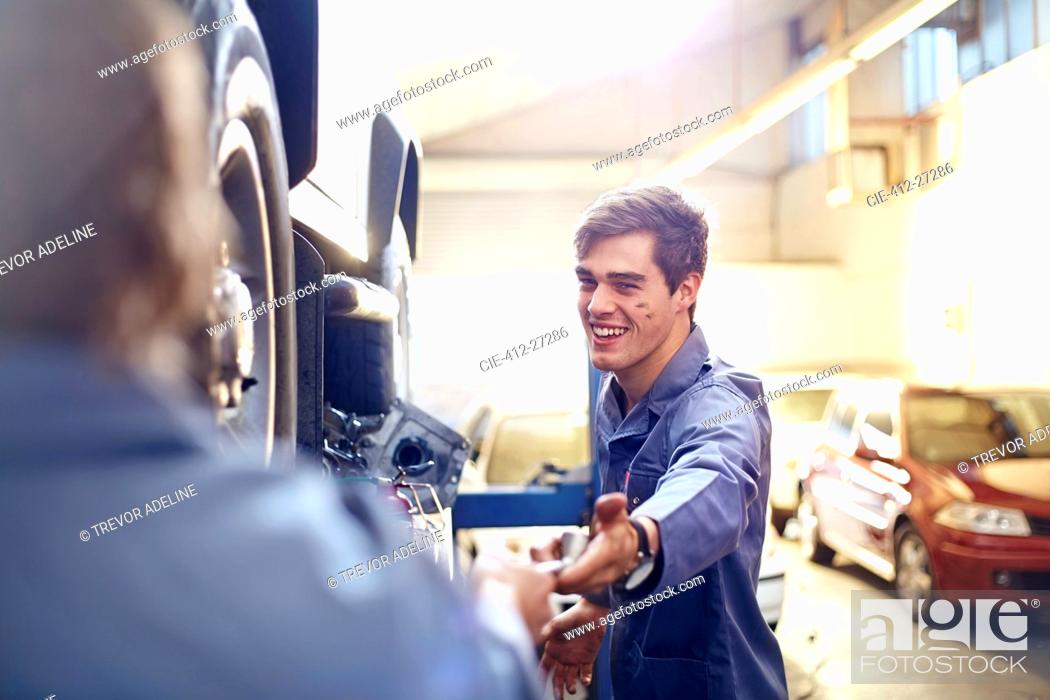 Stock Photo: Mechanic reaching for tool in auto repair shop.