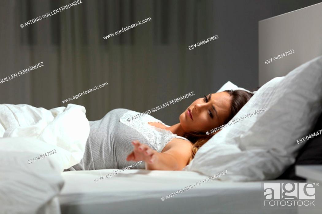 Stock Photo: Sad single woman missing her husband in the night on a bed at home.