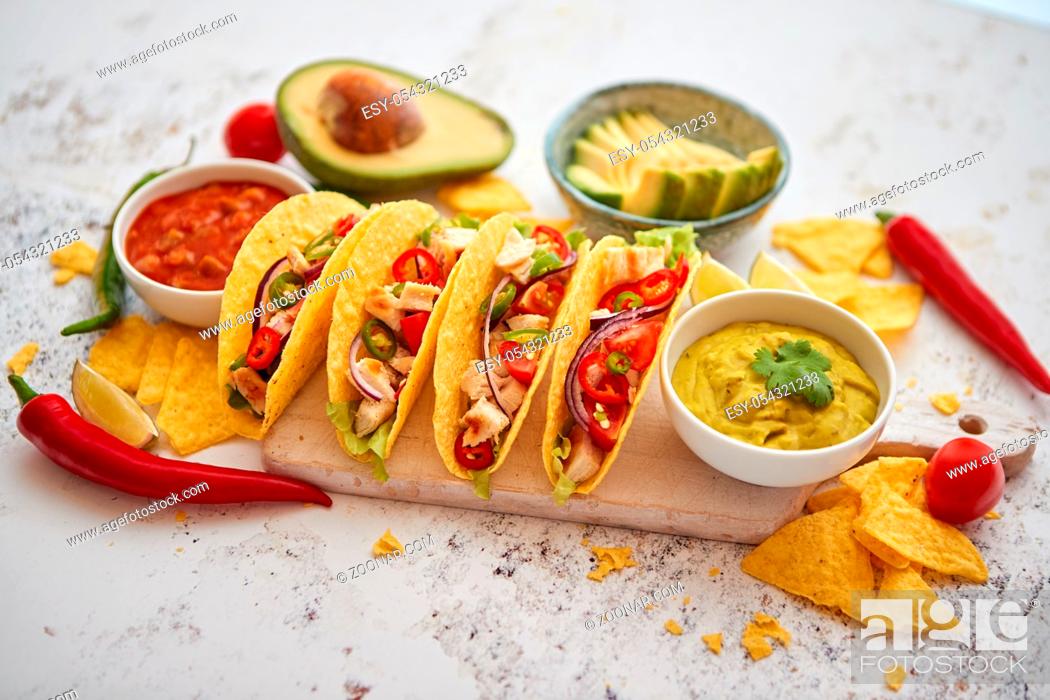 Stock Photo: Delicious Mexican fresh crispy tacos are served on wooden board. Stuffed with grilled chicken, spicy pepper, onion, tomato and more.