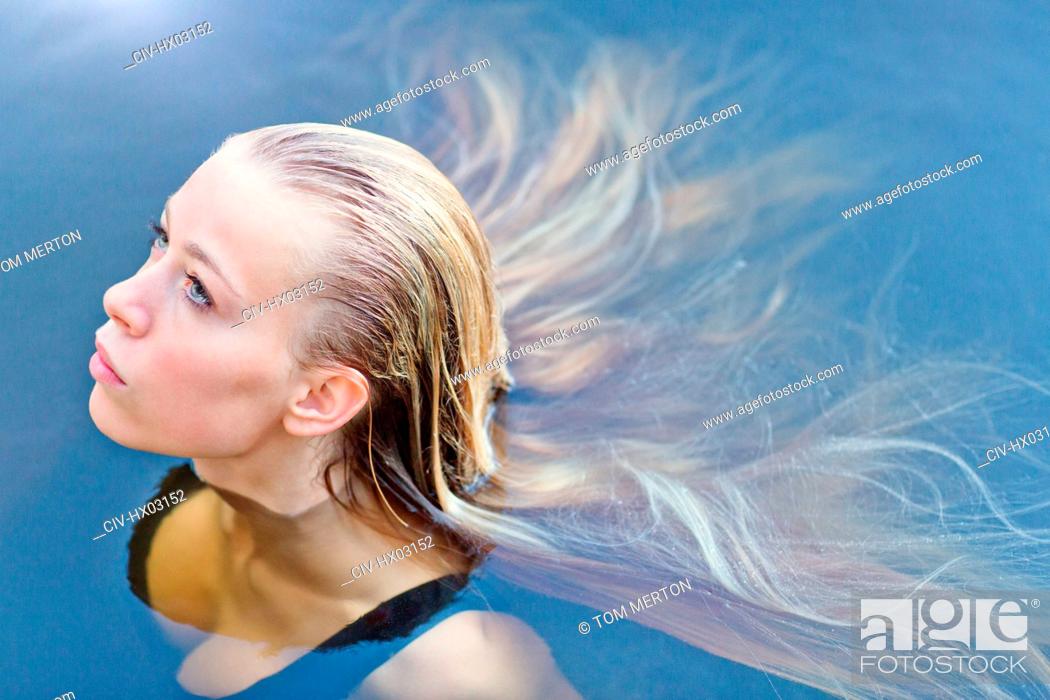 Stock Photo: Portrait beautiful blonde teenage girl with long hair floating in swimming pool.