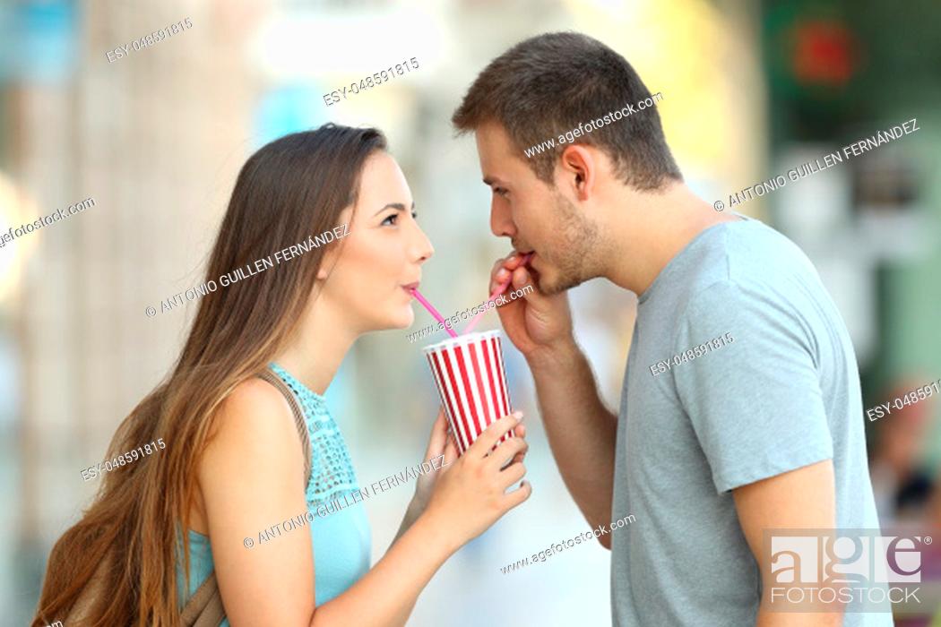 Stock Photo: Side view portrait of a happy couple sharing a takeaway refreshment in the street.