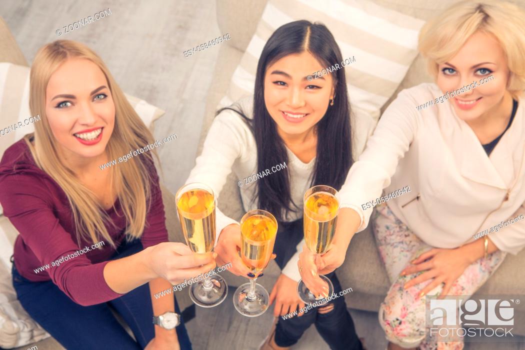 Stock Photo: Toned top view picture of best friends girls drinking champagne while spending free time having party at home. Beautiful women smiling for camera.