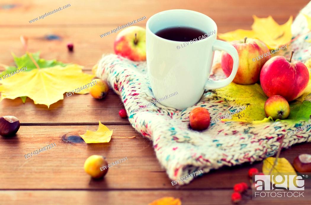 Stock Photo: season, drink and morning concept - close up of tea cup on wooden table with autumn leaves and scarf.