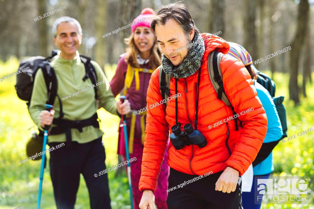 Stock Photo: Man wearing binoculars trekking with friends in forest.