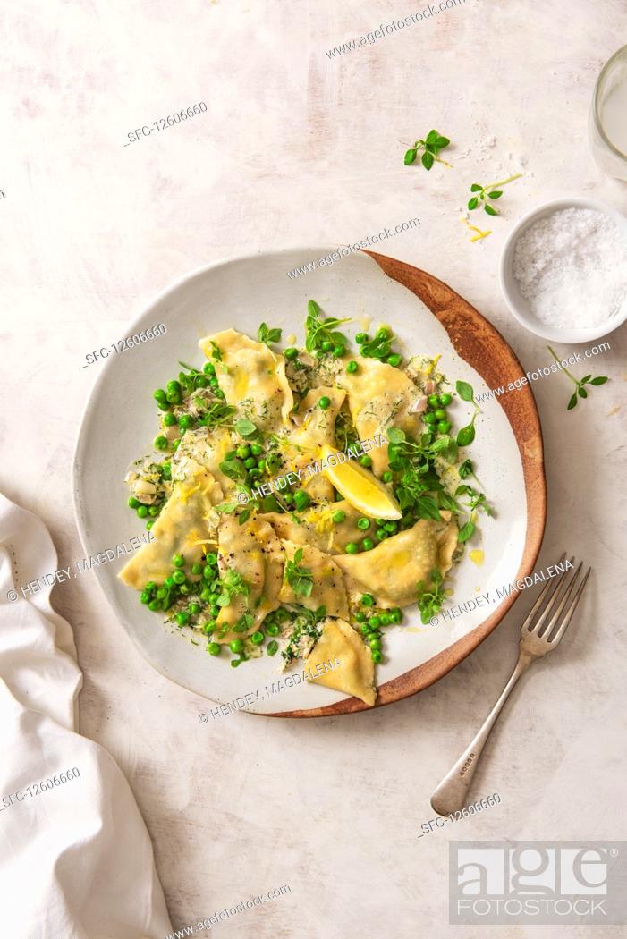 Stock Photo: Homemade spinach, ricotta and salmon ravioli with dill butter, peas and lemon.