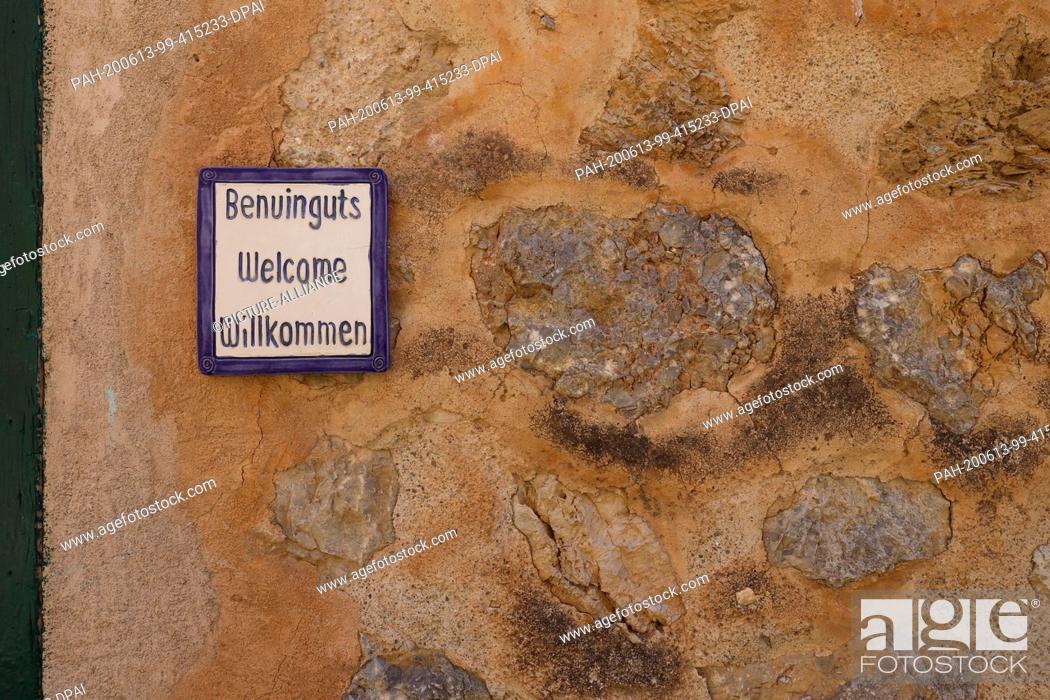 Stock Photo: 13 June 2020, Spain, Deia: A welcome sign, which can be seen in a street wall in the village, a municipality with many German inhabitants or owners of second.