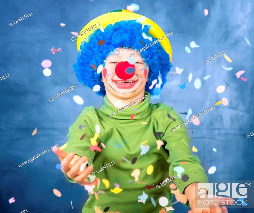 Stock Photo: young child dressed as a clown with wig and fake nose has fun playing with colorful confetti celebrating carnival.