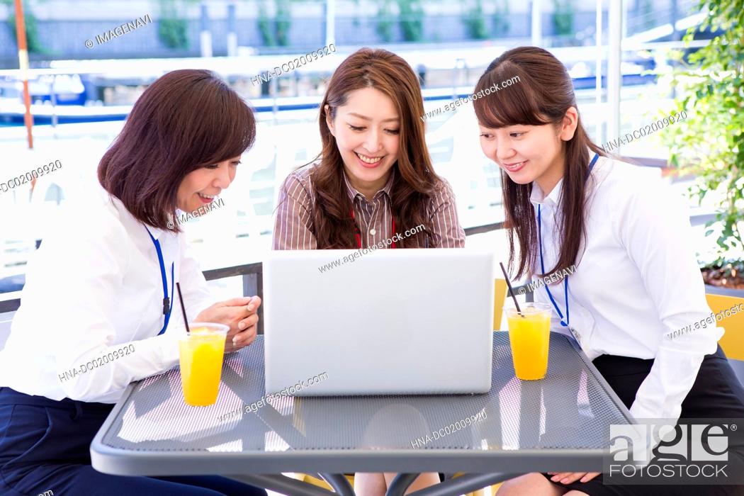 Stock Photo: Business women using a computer at an outdoor cafe.