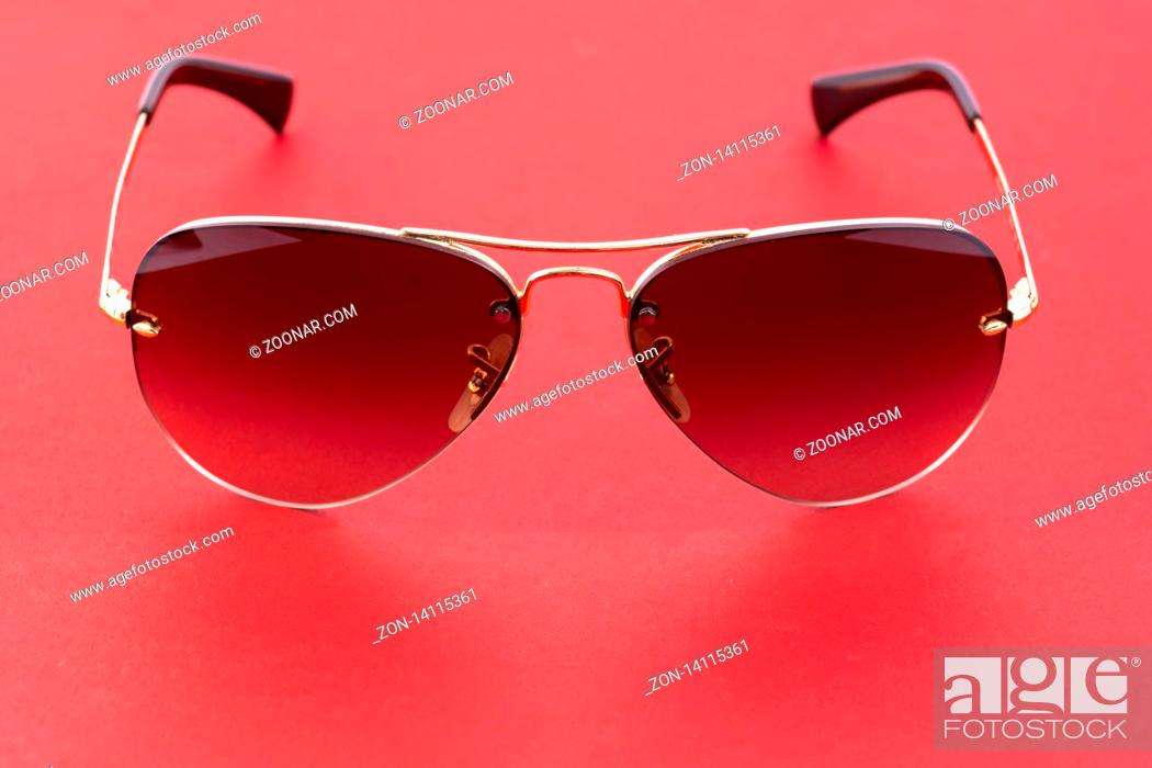 Stock Photo: Studio shot of brown aviator sunglasses on red background.