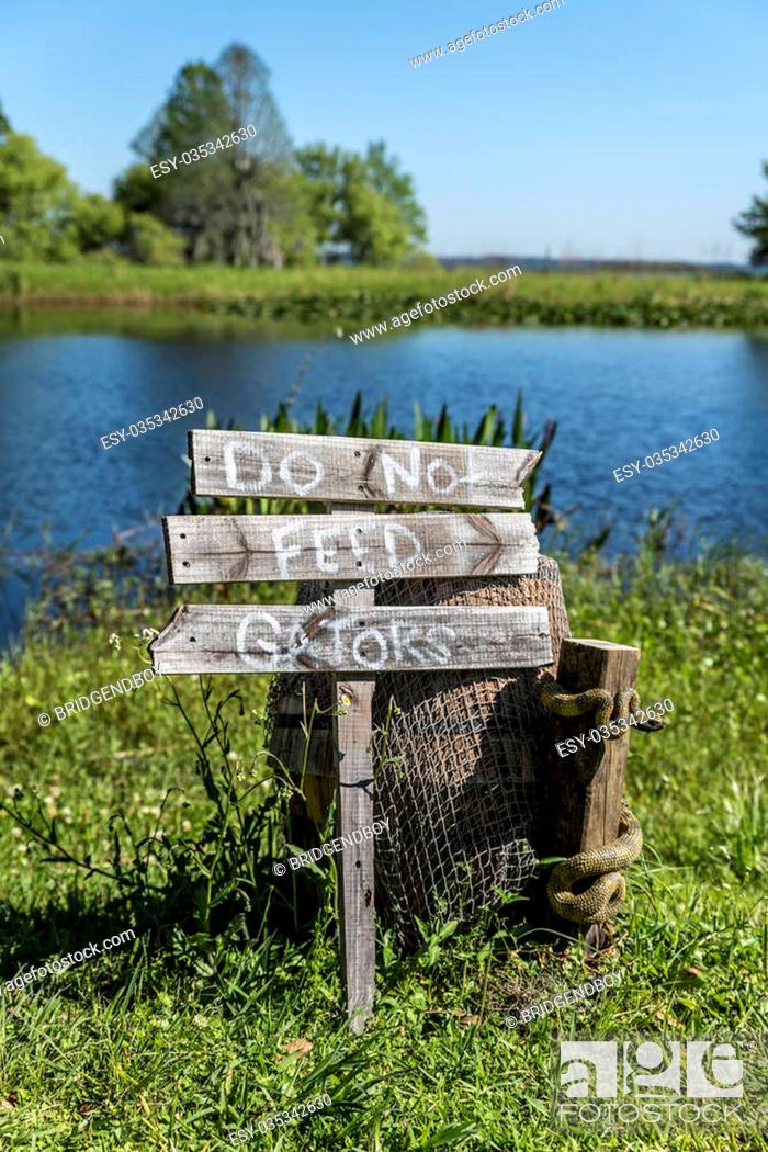Stock Photo: 'Do not feed that Gators' wooden sign post, beside a lake in the American deep south.