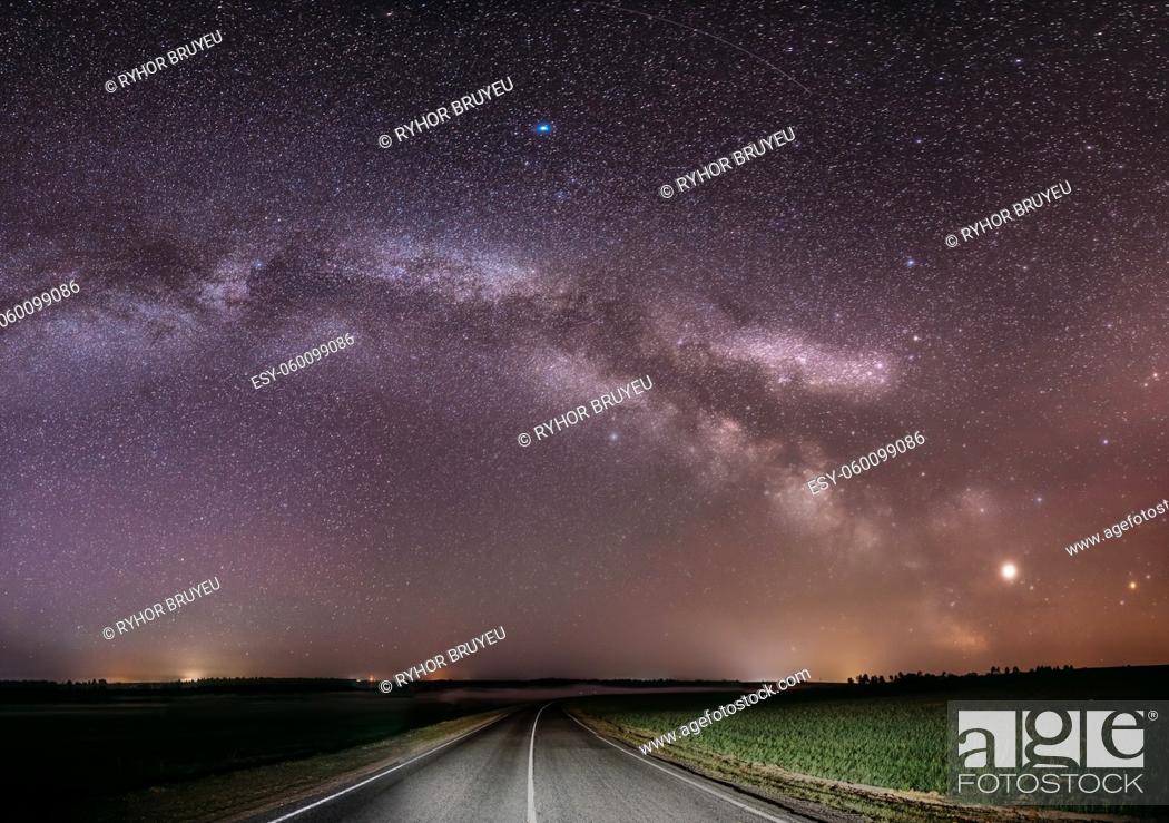 Photo de stock: Magenta Night Starry Sky Above Country Asphalt Road In Countryside And Green Field. Night View Of Natural Glowing Stars And Milky Way Galaxy.